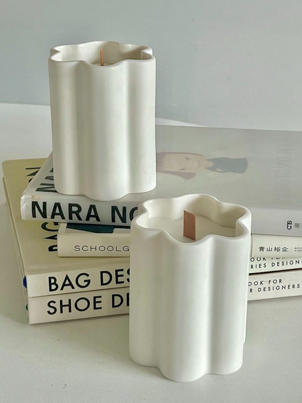 White wave-shaped ceramic candle holders on books