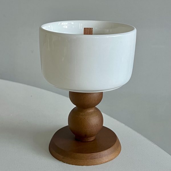 White ceramic candle holder with a wooden base.