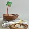 Natural coconut shell candle holder with a palm tree decoration