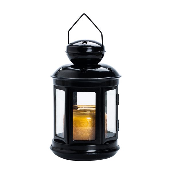 Black vintage lantern candle holder with glass panels and a lit candle inside.