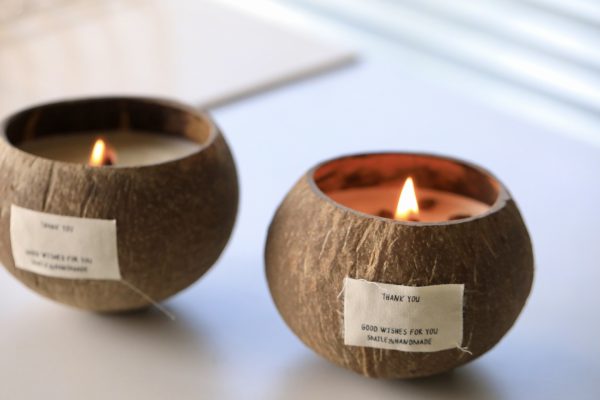 Handmade coconut shell candles with 'Thank You' labels burning softly