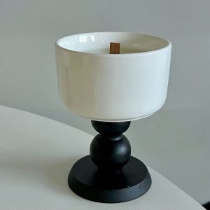 White ceramic candle holder with a black wooden base