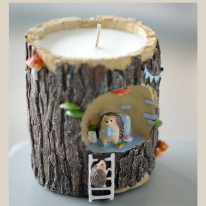 Candle in a tree trunk-shaped holder with a hedgehog decoration